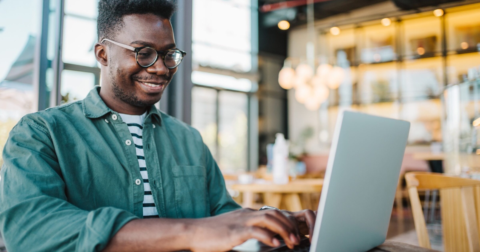 Man smiling and working on laptop at a table