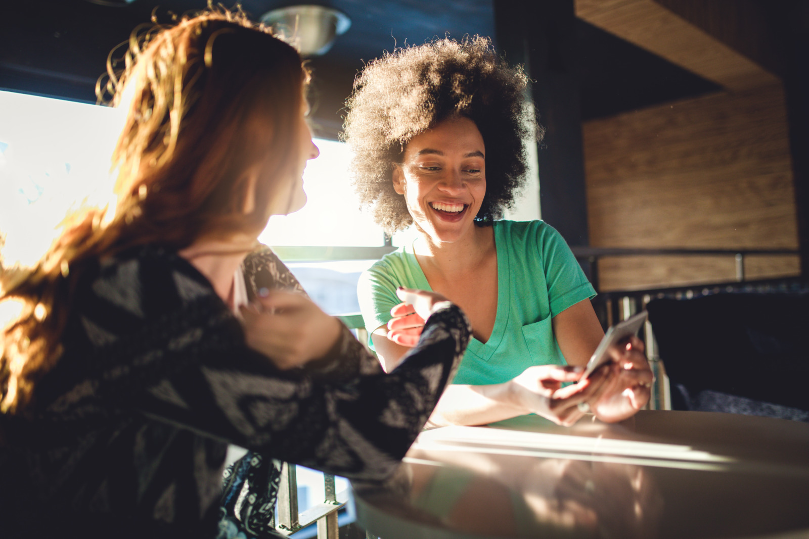 Two friends looking at their mobile phone at a cafe