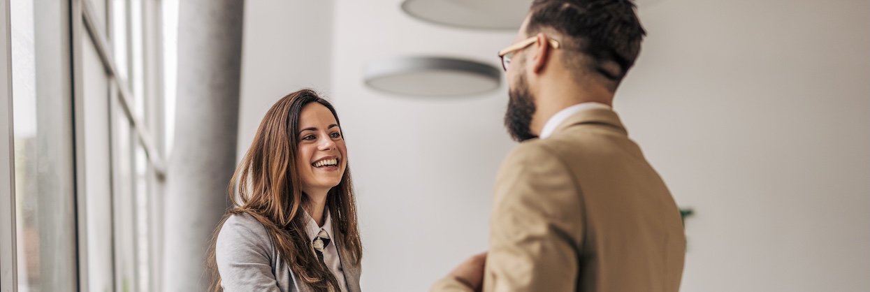 Businesswoman shaking hand of businessman in modern office